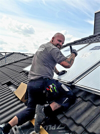 Ein Mitarbeiter von Breman beim installieren einer Solaranlage auf einem Hausdach.